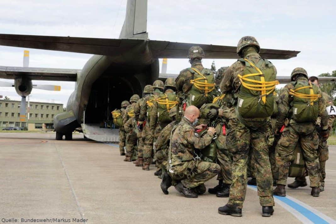 Der Absetzer, ein Sicherheitskontrolleur, überprüft ein letztes Mal, die angelegten Sprunggepäcke bei den Fallschirmjägern, bevor sie in die Transall C-160 einsteigen. (Quelle: Bundeswehr,