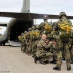 Der Absetzer, ein Sicherheitskontrolleur, überprüft ein letztes Mal, die angelegten Sprunggepäcke bei den Fallschirmjägern, bevor sie in die Transall C-160 einsteigen. (Quelle: Bundeswehr,