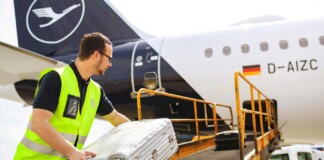 Loader places suitcases on the conveyor belt for loading a Lufthansa Airbus